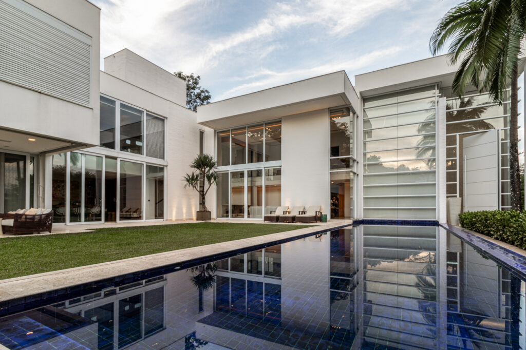 casa contemporânea com fachada branca e piscina espelhada em condomínio fechado
